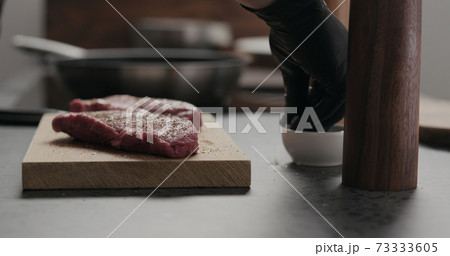 man salting raw beef steak on oak board man salting raw beef steak on oak board 73333605