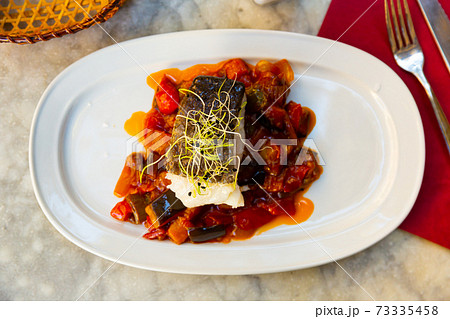 cuisine spanish candied fish with stewed vegetables served on white plate 73335458