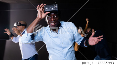 Afro-american man with friends playing video games using virtual reality glasses 73335993