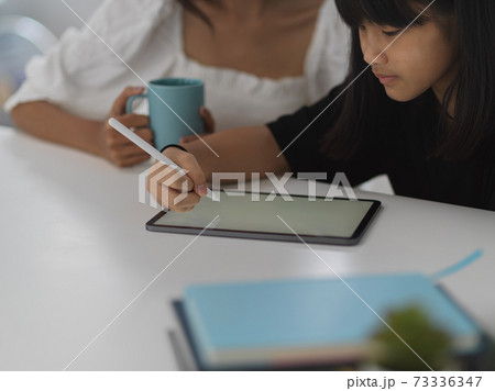 Female tutor teaching her student with tablet in living room Female tutor teaching her student with tablet in living room 73336347