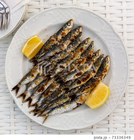 Malaga cuisine grilled sardines served with lemon on white plate on wooden table Malaga cuisine grilled sardines served with lemon on white plate on wooden table 73336349