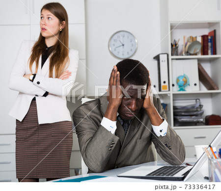 Tired man manager sitting at table and angry woman boss 73336417