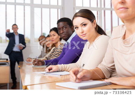 Young woman studying with colleagues at classroom 73336425