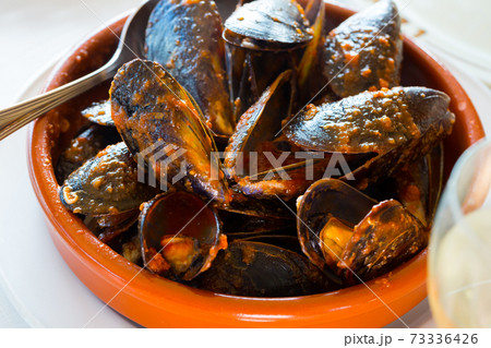 Picture of baked tasty mussels on a bowl with spoon Picture of baked tasty mussels on a bowl with spoon 73336426