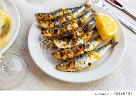 Malaga cuisine grilled sardines served with lemon on white plate on wooden table Malaga cuisine grilled sardines served with lemon on white plate on wooden table 73336437