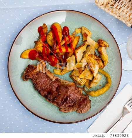 Veal steak with grilled potato and artichokes Veal steak with grilled potato and artichokes 73336928