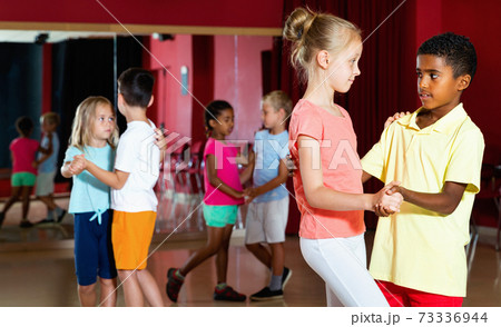 Group of positive childrens trying dancing with partner in class 73336944