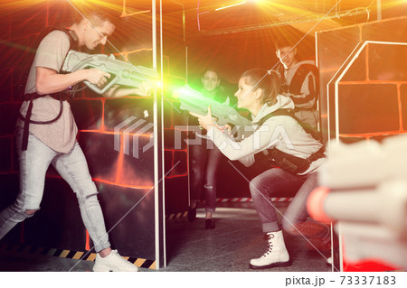 Group of young people playing laser tag game with laser guns Group of young people playing laser tag game with laser guns 73337183