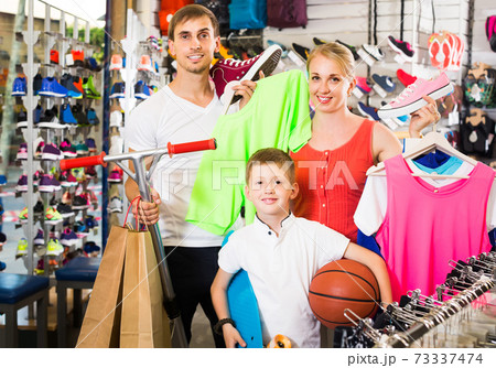 Couple with boy choosing shoes in sport shop 73337474