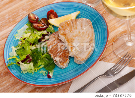 Scandinavian cuisine seafood served with greens and vegetables on plate on wooden table Scandinavian cuisine seafood served with greens and vegetables on plate on wooden table 73337576