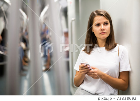 Woman using phone in subway car Woman using phone in subway car 73338692