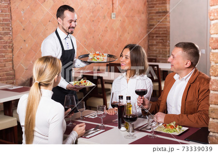 Ordinary male waiter carrying order for visitors Ordinary male waiter carrying order for visitors 73339039