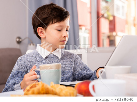 Boy looking to display laptop at the table in the kitchen Boy looking to display laptop at the table in the kitchen 73339040