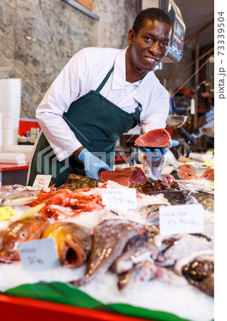 Salesman offering fresh fish Salesman offering fresh fish 73339504