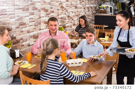 Woman is bringing salad and juice to young visitors Woman is bringing salad and juice to young visitors 73340172