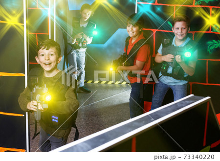 boy aiming laser gun at other players during lasertag game 73340220