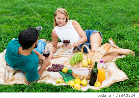Smiling couple is lying with wineglasses and talking 73340524