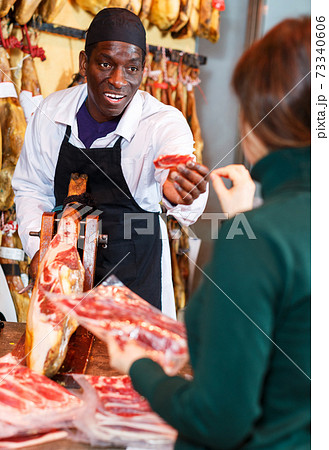 Salesman selling jamon to woman 73340606