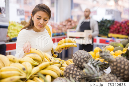 Woman picks ripe bananas at grocery supermarket 73340628