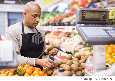 Man working in supermarket near fruit section 73340719