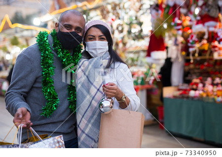 Married couple in protective masks with gifts at new year fair Married couple in protective masks with gifts at new year fair 73340950
