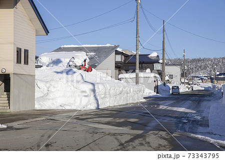 住宅の屋根から落ちた雪の除雪風景 73343795