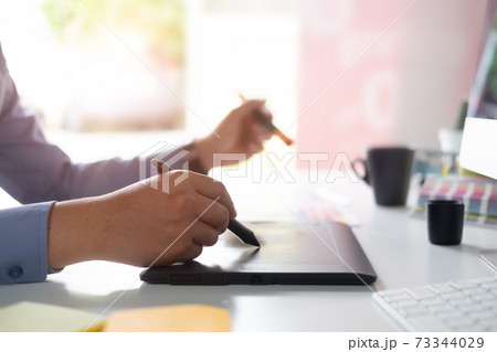 Hands of Graphic designer working with digital tablet and mouse pen on table and morning light. Hands of Graphic designer working with digital tablet and mouse pen on table and morning light. 73344029