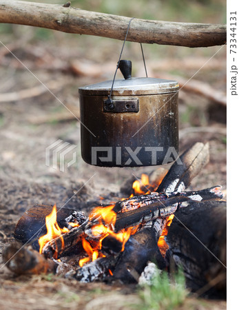 Outdoor cooking in old sooty cauldron on campfire Outdoor cooking in old sooty cauldron on campfire 73344131