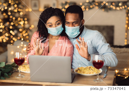 Black couple in masks waving to laptop 73347041