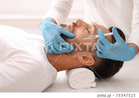 Cosmetologist doing anti-aging procedure for middle-aged man in clinic Cosmetologist doing anti-aging procedure for middle-aged man in clinic 73347523