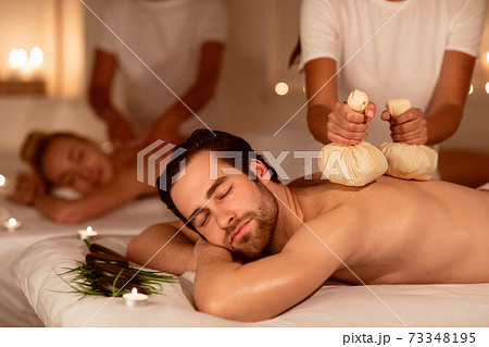 Couple Relaxing During Herbal Back Massage With Aromatic Bags Indoors Couple Relaxing During Herbal Back Massage With Aromatic Bags Indoors 73348195