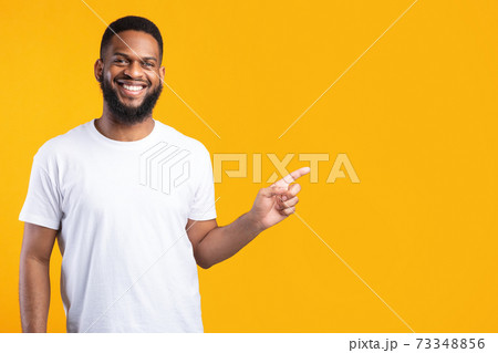 Black Man Pointing Finger Aside Standing Over Yellow Studio Background Black Man Pointing Finger Aside Standing Over Yellow Studio Background 73348856