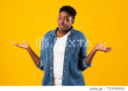 Puzzled Plus-Size Black Woman Shrugging Shoulders Over Yellow Background Puzzled Plus-Size Black Woman Shrugging Shoulders Over Yellow Background 73349493