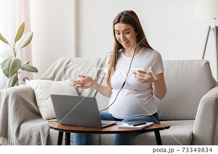 Web Conference. Cheerful pregnant woman having video call on laptop at home Web Conference. Cheerful pregnant woman having video call on laptop at home 73349834