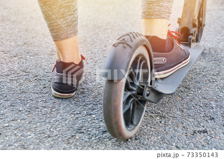 Legs of a man riding a scooter on the street. 73350143