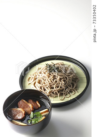 ロースト鴨肉と焼長葱と三つ葉の入った鴨せいろ蕎麦を白背景で撮影 73350402