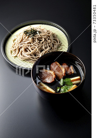 ロースト鴨肉と焼長葱と三つ葉の入った鴨せいろ蕎麦を黒背景で撮影 73350481