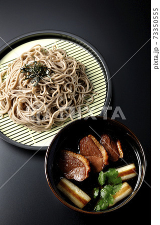 ロースト鴨肉と焼長葱と三つ葉の入った鴨せいろ蕎麦を黒背景で撮影（俯瞰） 73350555
