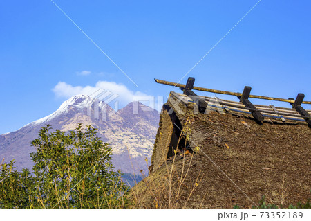 積雪の由布岳と茅葺き屋根 73352189