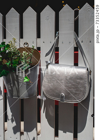 Festive evening small silver bag on a white rustic fence. Luxury accessories and party concept. 73352459