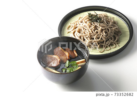 ロースト鴨肉と焼長葱と三つ葉の入った熱々の鴨せいろ蕎麦を白背景で撮影 73352682