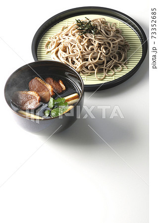 ロースト鴨肉と焼長葱と三つ葉の入った熱々の鴨せいろ蕎麦を白背景で撮影 73352685