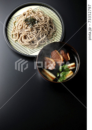 ロースト鴨肉と焼長葱と三つ葉の入った鴨せいろ蕎麦を黒背景で撮影（俯瞰） 73352797