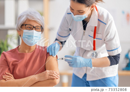 Doctor giving a senior woman a vaccination 73352808