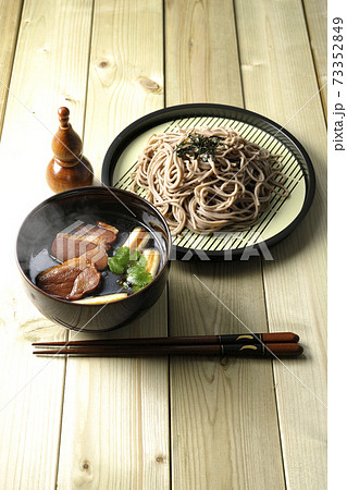 ロースト鴨肉と焼長葱と三つ葉の入った熱々の鴨せいろ蕎麦と瓢箪型の七味入れと箸 73352849