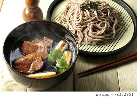 ロースト鴨肉と焼長葱と三つ葉の入った熱々の鴨せいろ蕎麦と瓢箪型の七味入れと箸 73352851