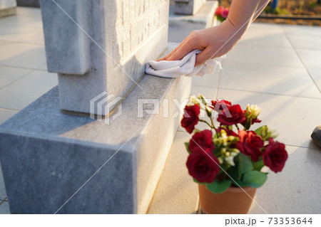 Cleaning cemetery. A woman's hand washes grey monument at the grave with rag 73353644