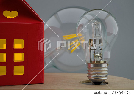 Light bulb and small house with warm light Light bulb and small house with warm light 73354235