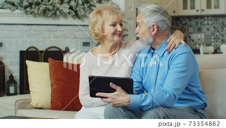 Retired senior couple at home buying products or services online using digital tablet. Coronavirus quarantine lockdown. 73354862
