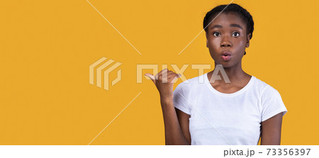 Shocked African American Lady Pointing Thumb Aside, Studio Shot 73356397